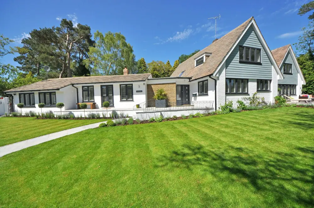 A white cottage style home with dark trim and a freshly cut lawn